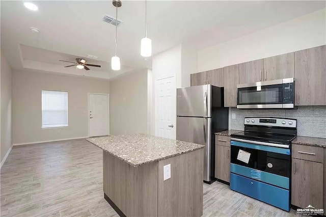 4905 N Hiawatha Dr, Pharr, TX 78577 - kitchen featuring stainless steel appliances, a tray ceiling, a center island, a ceiling fan, and light stone counters