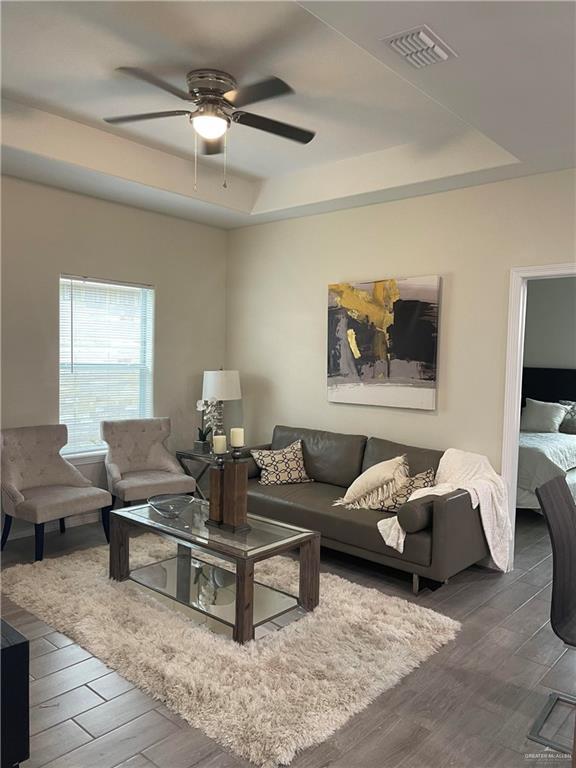 4905 N Hiawatha Dr, Pharr, TX 78577 - living room featuring a raised ceiling, wood finished floors, and a ceiling fan