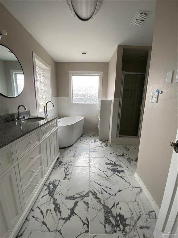 bathroom with shower with separate bathtub, tile walls, and vanity