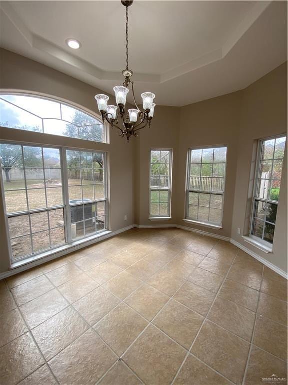 spare room with an inviting chandelier, a raised ceiling, light tile patterned flooring, and a high ceiling