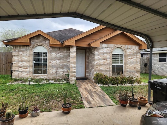 exterior space with a shingled roof, fence, a lawn, and brick siding