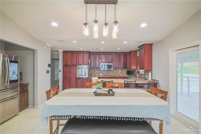 kitchen featuring pendant lighting, backsplash, light tile patterned floors, and stainless steel appliances