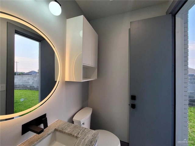 bathroom with plenty of natural light, vanity, and toilet