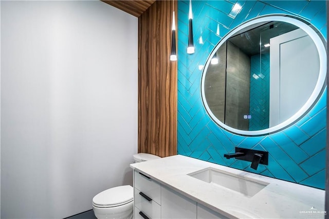 bathroom with vanity, toilet, and tile walls