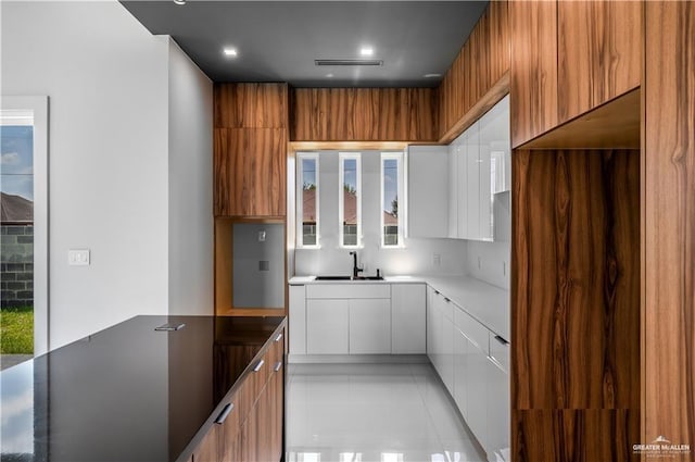 kitchen featuring light tile patterned flooring, white cabinetry, and sink