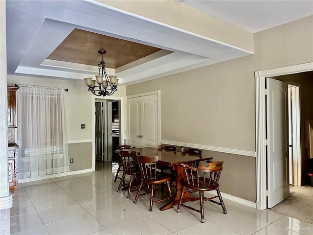 dining room with a chandelier, a tray ceiling, and light tile patterned flooring