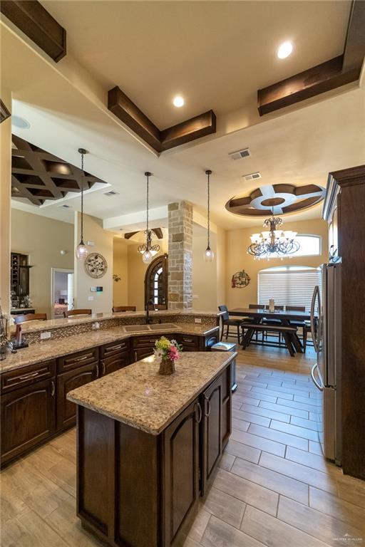 816 Samaria St, Weslaco, TX 78596 - kitchen with freestanding refrigerator, dark brown cabinets, a sink, pendant lighting, and recessed lighting