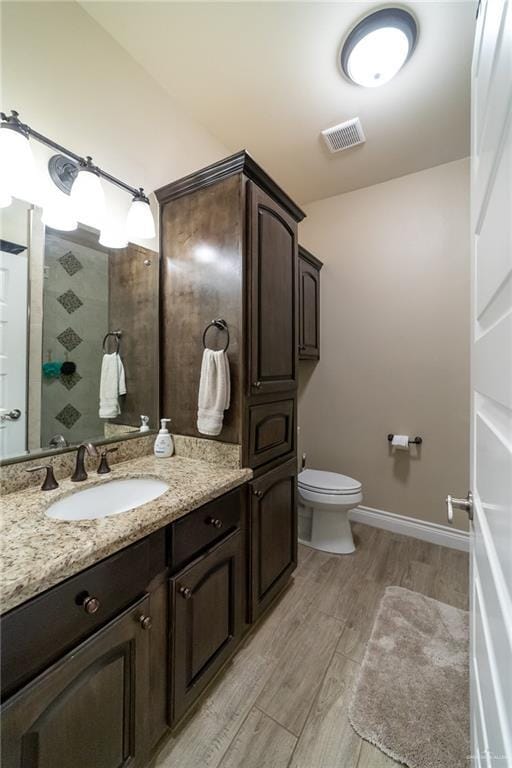 816 Samaria St, Weslaco, TX 78596 - full bathroom with a tile shower, toilet, wood finished floors, vanity, and baseboards