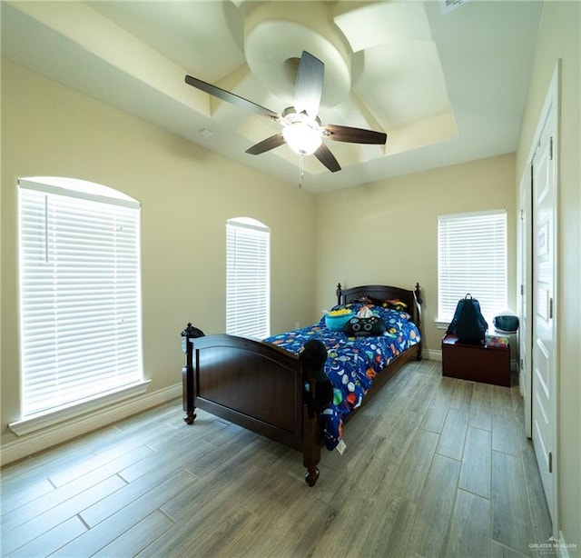 816 Samaria St, Weslaco, TX 78596 - bedroom with wood finished floors, baseboards, a tray ceiling, and a ceiling fan