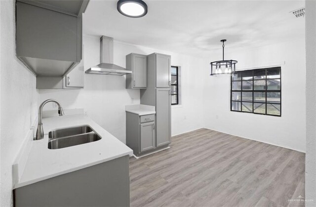 kitchen featuring gray cabinets, sink, wall chimney exhaust hood, and pendant lighting