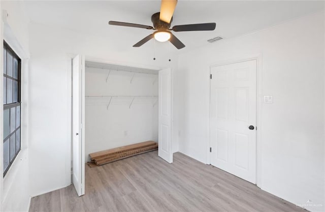 unfurnished bedroom featuring ceiling fan, light wood-type flooring, and a closet