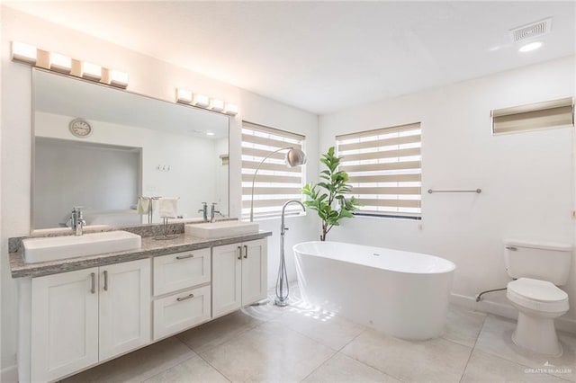 bathroom featuring toilet, a washtub, vanity, and tile patterned flooring