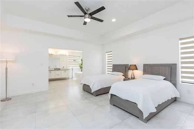 bedroom featuring a raised ceiling, ceiling fan, and ensuite bathroom