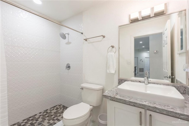 bathroom with vanity, toilet, and a tile shower