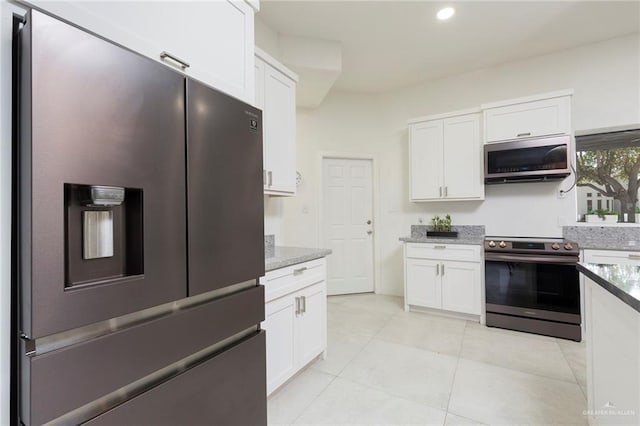 kitchen with light stone countertops, light tile patterned floors, stainless steel appliances, and white cabinetry