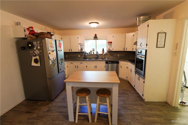 kitchen featuring a kitchen island, dark hardwood / wood-style flooring, white cabinetry, and appliances with stainless steel finishes