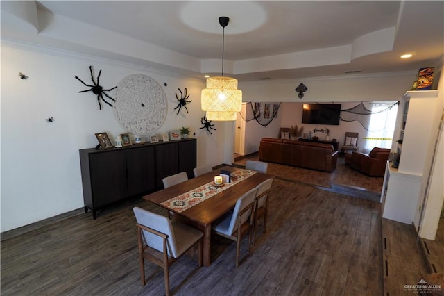 dining area featuring a raised ceiling, dark hardwood / wood-style flooring, and ornamental molding