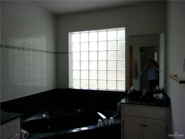 bathroom with a tub to relax in, vanity, and a textured ceiling