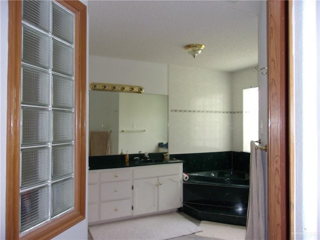 bathroom featuring a washtub, a textured ceiling, and vanity