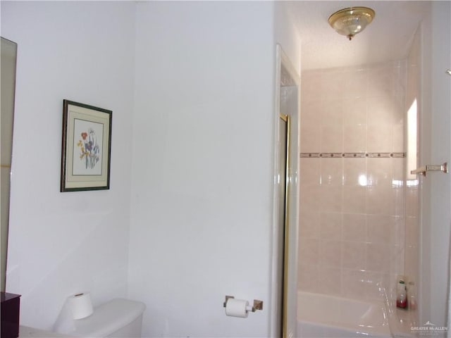 bathroom with tiled shower / bath combo and toilet