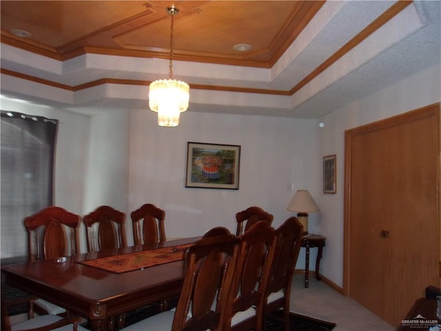 carpeted dining area with a raised ceiling, an inviting chandelier, and ornamental molding