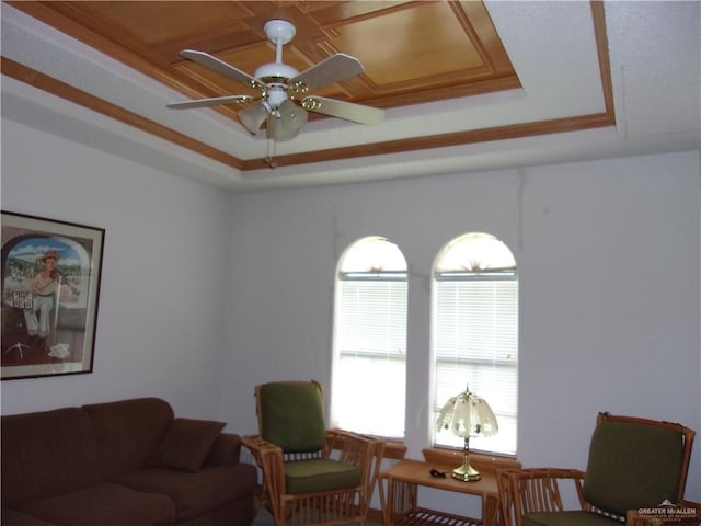 living room with a tray ceiling, ceiling fan, and ornamental molding