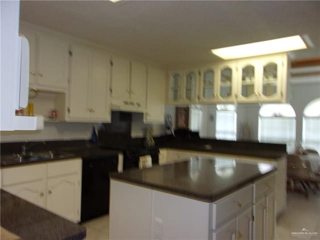 kitchen featuring white cabinets, a kitchen island, light tile patterned floors, and sink