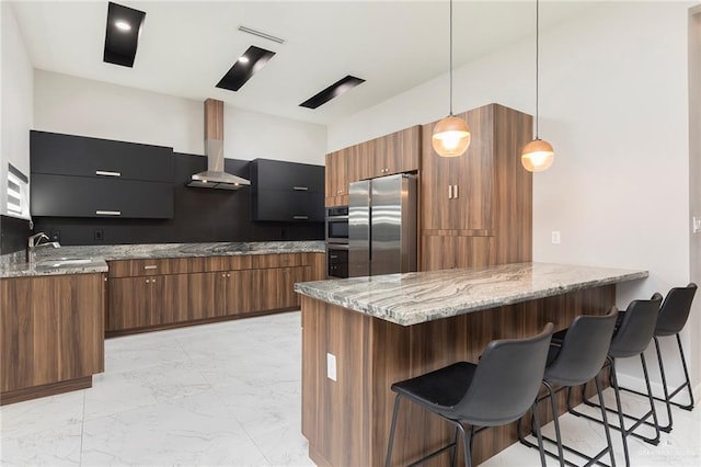 kitchen featuring range hood, brown cabinetry, marble finish floor, and appliances with stainless steel finishes