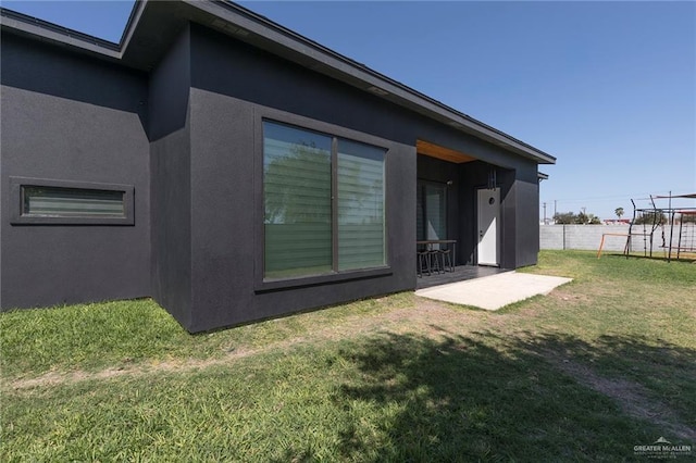 rear view of property featuring stucco siding, fence, a playground, a yard, and a patio area