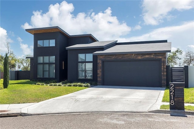 modern home with stucco siding, driveway, fence, a front yard, and an attached garage