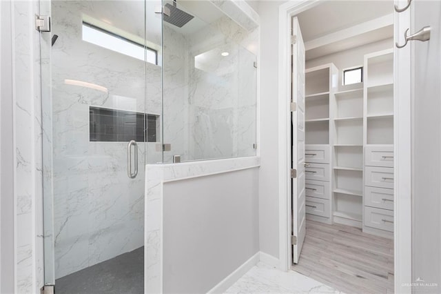 bathroom with a marble finish shower, marble finish floor, and a walk in closet