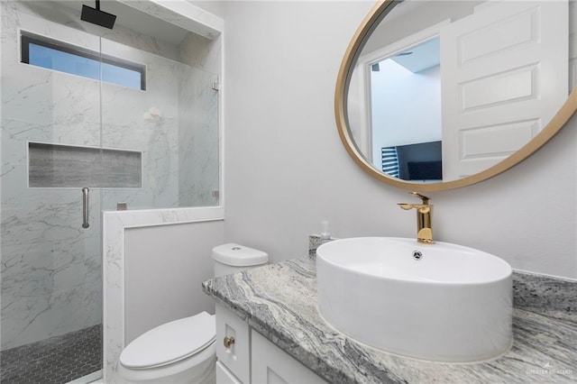 bathroom featuring a marble finish shower, toilet, and vanity