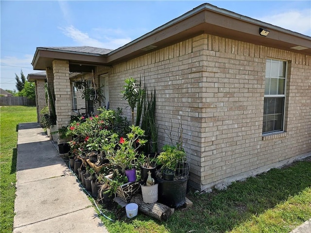 view of property exterior featuring brick siding and fence
