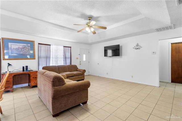 living room with light tile patterned floors, a textured ceiling, a raised ceiling, and ceiling fan