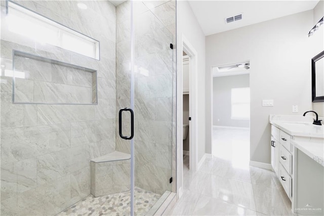 bathroom featuring vanity, a shower with door, toilet, and a wealth of natural light