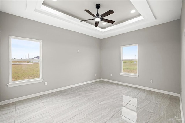 empty room featuring a tray ceiling and ceiling fan