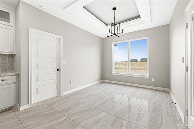 unfurnished dining area featuring a raised ceiling and a notable chandelier