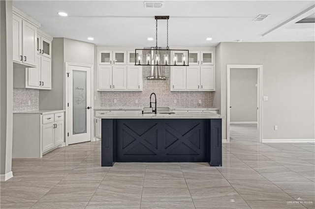 kitchen with white cabinets, an island with sink, decorative light fixtures, and sink