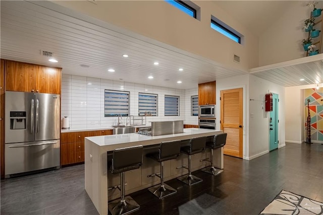 2411 Holland Ave, Edinburg, TX 78539 - kitchen featuring stainless steel appliances, brown cabinetry, a sink, light countertops, and a high ceiling