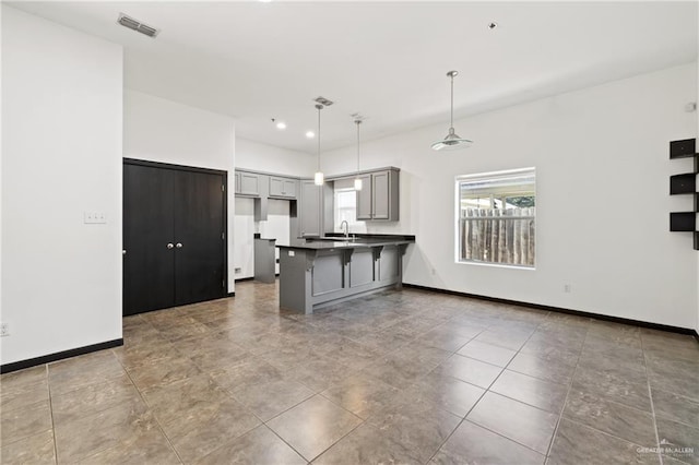 kitchen with pendant lighting, a kitchen bar, sink, kitchen peninsula, and gray cabinetry