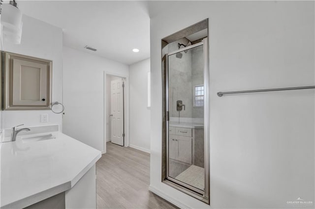 bathroom with a stall shower, wood finished floors, vanity, baseboards, and recessed lighting