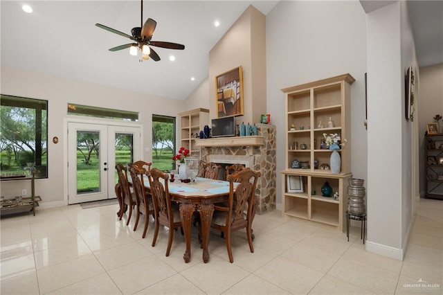 tiled dining space featuring a fireplace, french doors, high vaulted ceiling, and ceiling fan