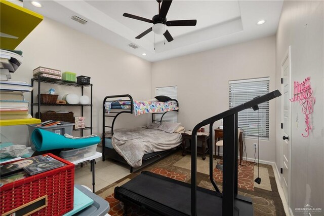 exercise room with a tray ceiling and ceiling fan