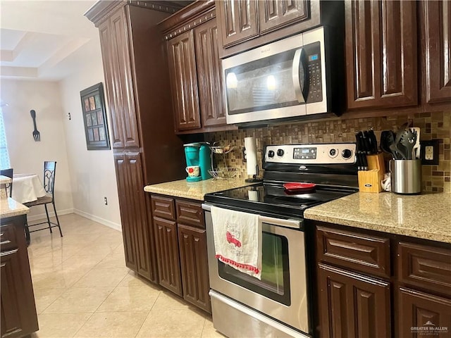 kitchen featuring tasteful backsplash, light stone countertops, stainless steel appliances, and light tile patterned flooring