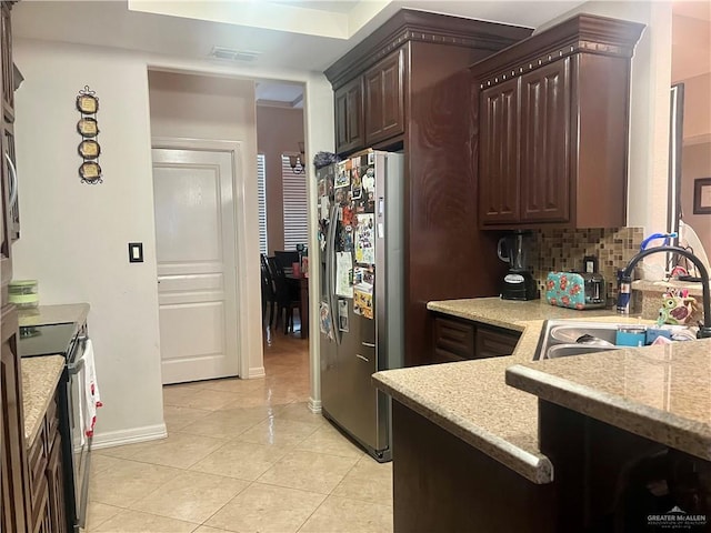 kitchen with dark brown cabinetry, sink, light tile patterned floors, appliances with stainless steel finishes, and decorative backsplash