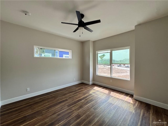 empty room with dark wood finished floors, baseboards, and plenty of natural light