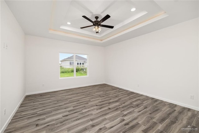 unfurnished room with dark hardwood / wood-style flooring, a raised ceiling, and ceiling fan