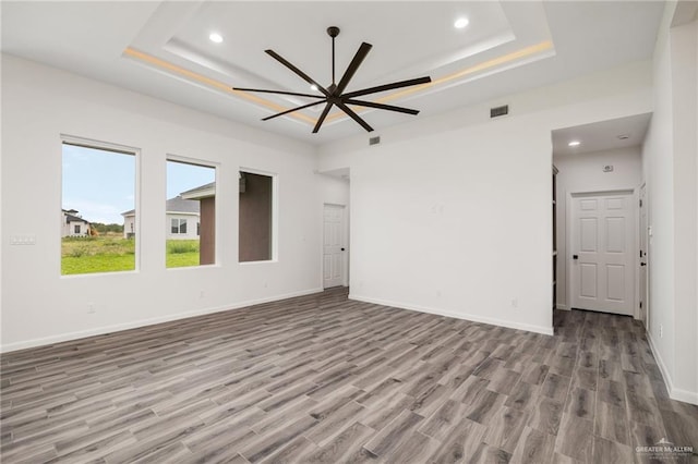 spare room with ceiling fan, light wood-type flooring, and a tray ceiling