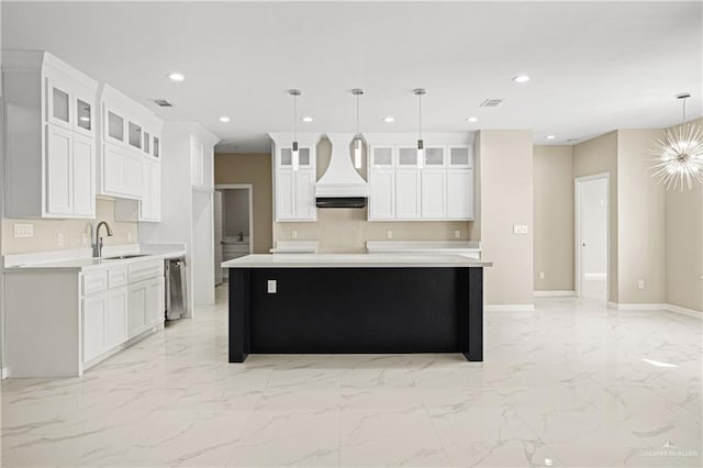 kitchen featuring white cabinets, a center island, decorative light fixtures, and sink