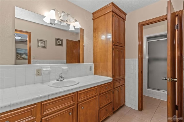 bathroom featuring tile patterned flooring, vanity, an enclosed shower, and a textured ceiling